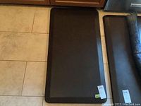 Photo of two black foam chef mats placed on tiled floor, showing top and side views with labels 815 and 816.