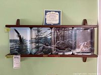 Four rectangular collector plates arranged side-by-side on wood rack, with certificate of authenticity behind center plate.