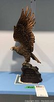 Front side view of the eagle sculpture showing detailed wings, head, and base with inscription plaque.