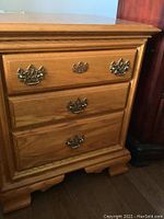 Front view showing three drawers and detailed brass hardware.