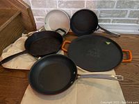 Photo of all five frying pans including the Lagostina grill pan with orange handles and four other skillets with different handles and surfaces