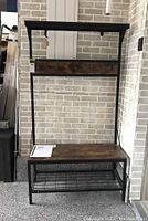 Frontal view of coat tree showing bench seat with laminated wood top, upper shelf, and five coat hooks on a wood panel