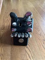 Entire cutlery set in black knife block showing knife handles and kitchen shears on wood floor