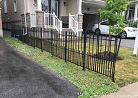 Overall view of ten joined black fence panels with posts installed along front yard