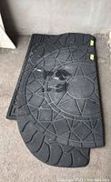 Four black outdoor mats stacked; two curved semicircle mats on top with star pattern, two rectangular mats underneath with geometric patterns.