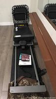 Folded reformer frame and carriage with foot bar, shoulder blocks, straps, DVDs and manuals on carriage