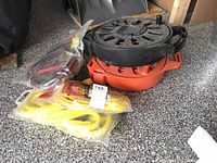 Photo showing three extension cord reels stacked, booster cables and yellow rope in front