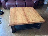 Top view of the square coffee table showing wood grain surface and black legs.