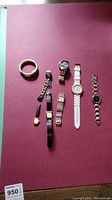 8 ladies wristwatches laid out on a burgundy mat, varied band materials and colors. One Timex watch with only half of the band visible.