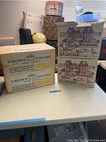 Four stacked boxes: two Crown Empire Fine China 28 piece starter sets and two Diamant Budown Crystal Stemware 12 piece sets.