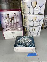 Overview photo showing multiple boxed sets of glassware and a buffet caddy silverware set on a table.