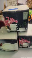Three boxed sets of Christopher Stuart Optima dish sets stacked showing floral designs and product information labels.