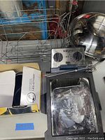 Krups deep fryer with control knobs, metal trays, and racks on a white surface