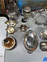 Overview of antique kitchen and home decor items with metal, brass, silver plated, and glass pieces, showing dust and staining.