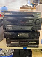 Front view of the stacked electronics showing RCA DVD player on top, two Kenwood units including stereo receiver and other component, and a cassette deck at the bottom