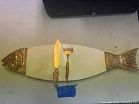 Top view of the fish-shaped marble plate with brass fish head and tail, displaying two utensil pieces placed on top.