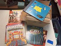 Photo showing a box filled with a collection of vinyl albums, top visible includes 'Gumdrop Follies' and 'Bambi' albums.