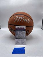 Front view of the signed basketball with JSA certificate in front showing certification number.