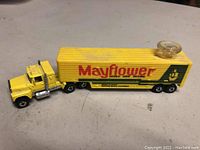 Side view of yellow Mayflower semi truck and trailer with steering wheel on top