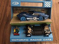 Blue Ideal Mako Shark Corvette racing car displayed on stand with separate chassis and motor assembly inside blue box with clear lid partially removed.