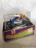 Front and top view of Chopcycles Blown Torch toy still in display blister on original boxed packaging. Blue and silver cycle with orange rider visible.