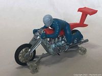 Side front view showing detailed chrome engine, blue rider with silver helmet, and red spoiler.