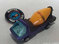 Purple metallic diecast cement mixer truck with badge in background