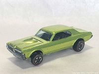 Front side view of green Hot Wheels Custom Cougar die-cast car showing some paint wear and redline tires.