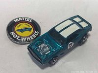 Top-down view of teal Heavy Chevy car and round Hot Wheels button badge