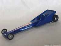 Side view of a blue vintage Hot Wheels Mongoose dragster showing front wheel, graphics and rear engine detail.