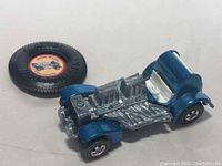 Front view of metallic blue car chassis and separate round promotional button badge