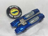 Top-down view of metallic blue double cockpit Hot Wheels Splittin' Image car with accompanying button badge.