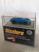 Blue metallic Ford Mk IV Hot Wheels Sizzlers electric toy car displayed inside original clear plastic box with labeling and branding visible. The box shows wear.