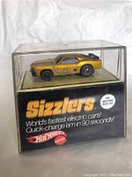 Front view of the car in original black display box showing branding and Sizzlers logo.