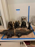 Photo showing assorted black bear figurines and two alligator bookends arranged on a table surface.