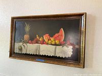 Full frontal view of the framed painting hanging on a white wall.