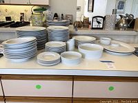 Full view of the set on kitchen counter showing multiple stacked plates, bowls, serving platter, and gravy pitcher.