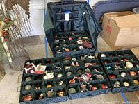 Full view of the four divided trays of Christmas ornaments inside the canvas zippered case with wheels