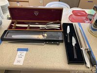 Top angle view showing cutlery carving set in wooden box, two knives in foam case, and a Hofritz sharpening steel.