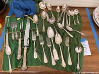 Assorted forks, carving set and spoons laid out on green roll