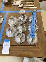 Overhead view of seven sterling silver candle holder bases on wooden table