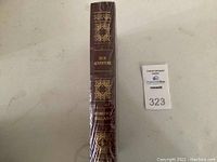 Spine view of dark brown leather-bound book titled "High Adventure" by Edmund Hillary, gilt decoration, shrink-wrapped