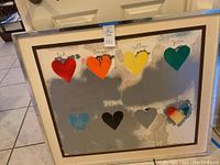 Front view of framed screenprint showing eight colored hearts on silver background
