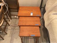 Full view of the three wooden nesting tables stacked from smallest to largest showing condition and size difference