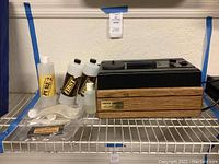 Nitty Gritty Record Cleaning Machine on metal shelf with cleaning solution bottles and accessories.