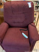 Front view of burgundy Pride lift chair with remote control on seat