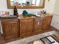 Full front view of the wooden buffet showing the four doors closed with decorative veneer and brass handles.