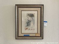 Framed artwork hanging on wall in silver-gold wood frame with double beige mat border.