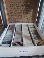 View of the white box with three compartments filled with hockey cards. Handwritten notes listing card types and special editions on the inside lid of the box.