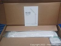 Boxed 44 LED desk lamp with instruction manual on top, visible in open box along with white lamp arm pieces wrapped in plastic.